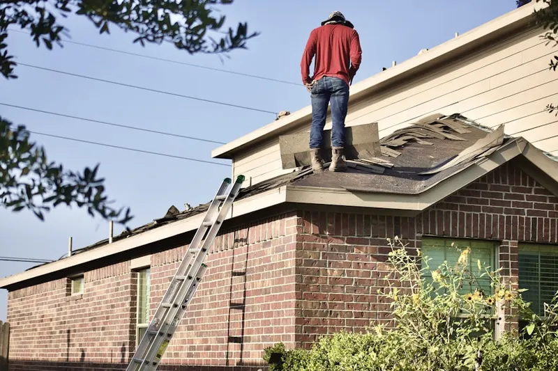Professional roofer working on a residential roof in Raynell